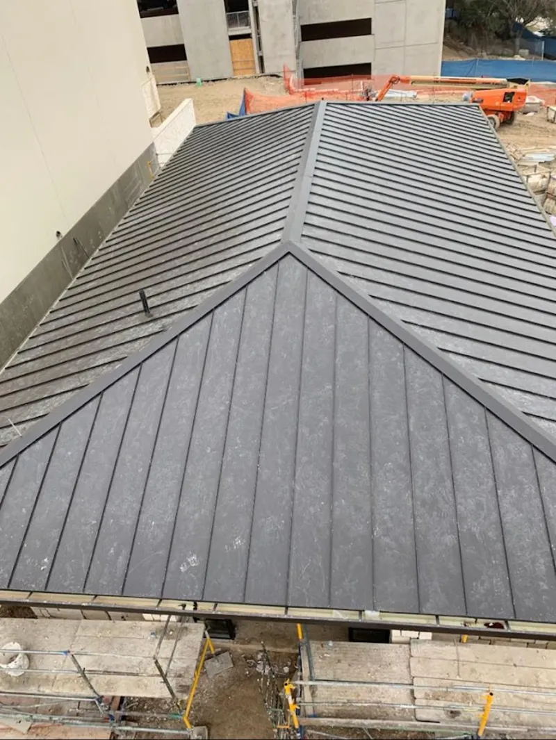 Commercial metal roof construction with crane equipment in Killingworth